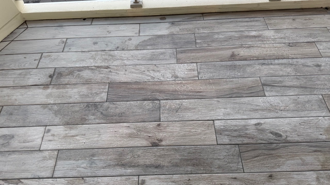 Détail des alignements et des joints d’un carrelage gris à effet bois.
