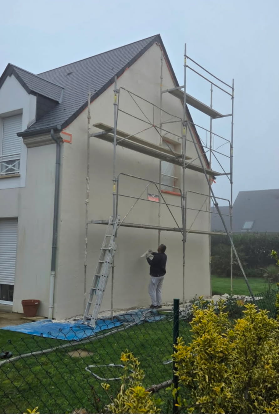 Application d’un enduit clair sur un pignon avec échafaudage lors d’un chantier à Cherbourg.