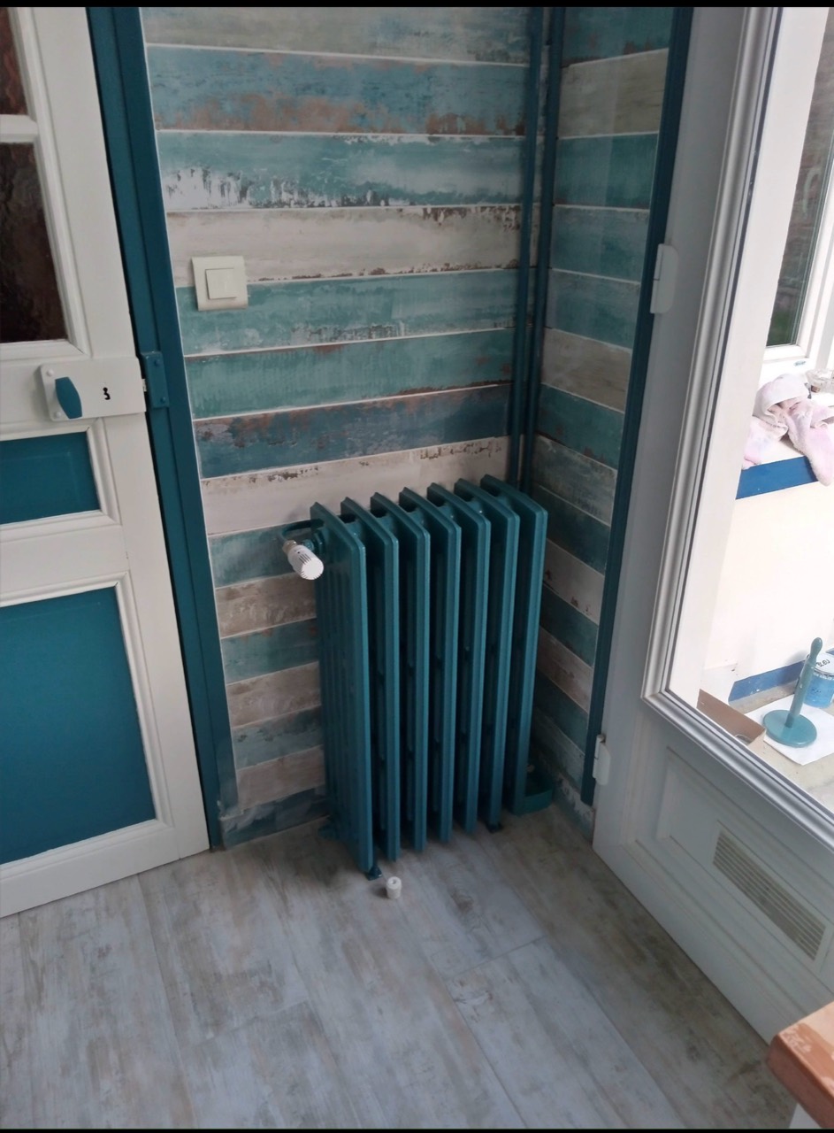 Radiateur peint et finitions bleu pétrole dans une cuisine rénovée.