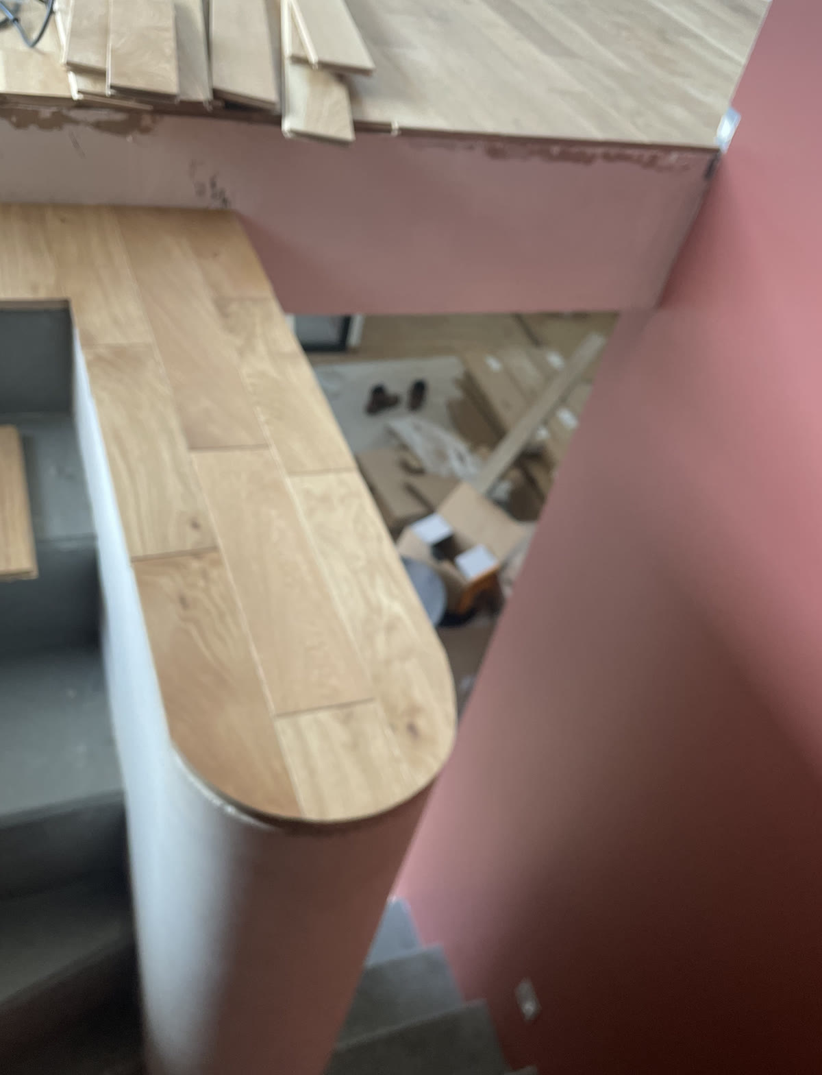Palier courbe en cours d’habillage avec un revêtement aspect bois autour d’une cage d’escalier.