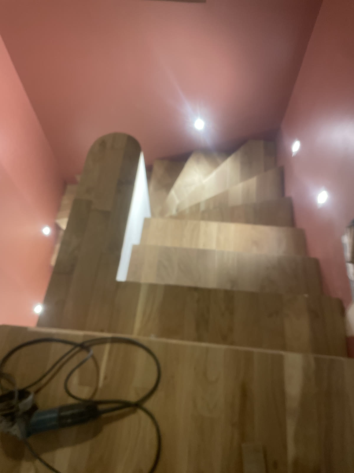 Escalier intérieur en cours d’habillage avec un revêtement aspect bois et des outils au premier plan.