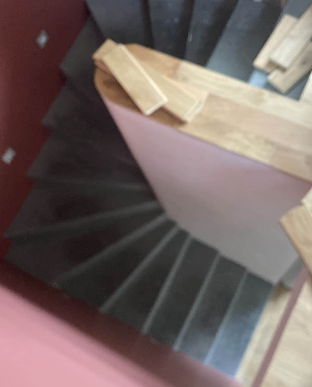 Vue en hauteur d’un escalier intérieur en préparation avec des éléments de finition aspect bois.