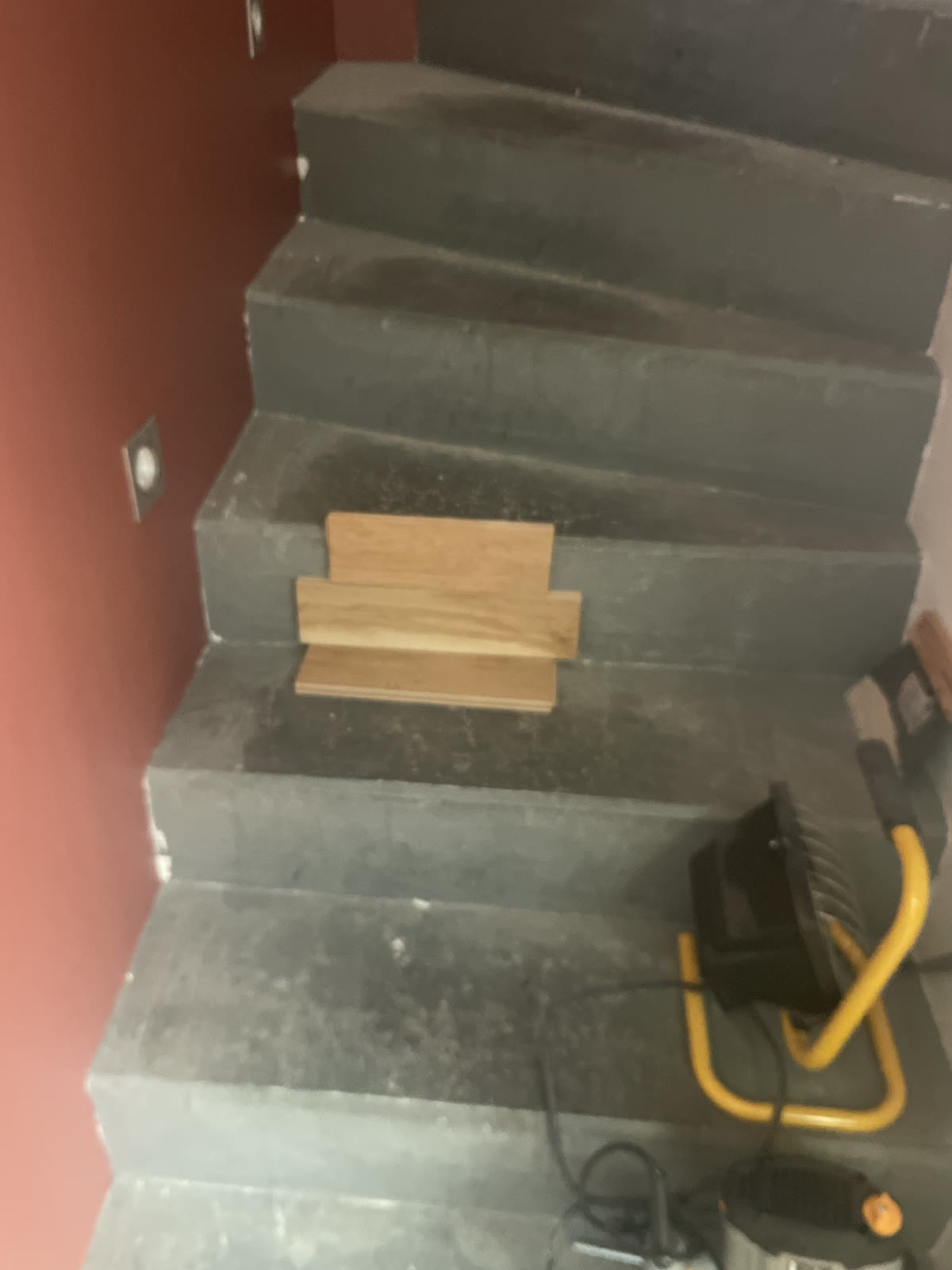 Escalier intérieur sombre en cours de préparation avec des éléments de revêtement aspect bois.