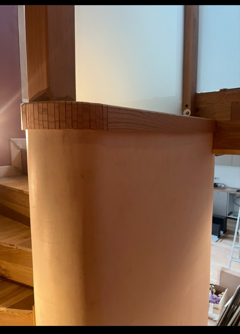 Détail d’une finition arrondie en bois sur un garde-corps intérieur.