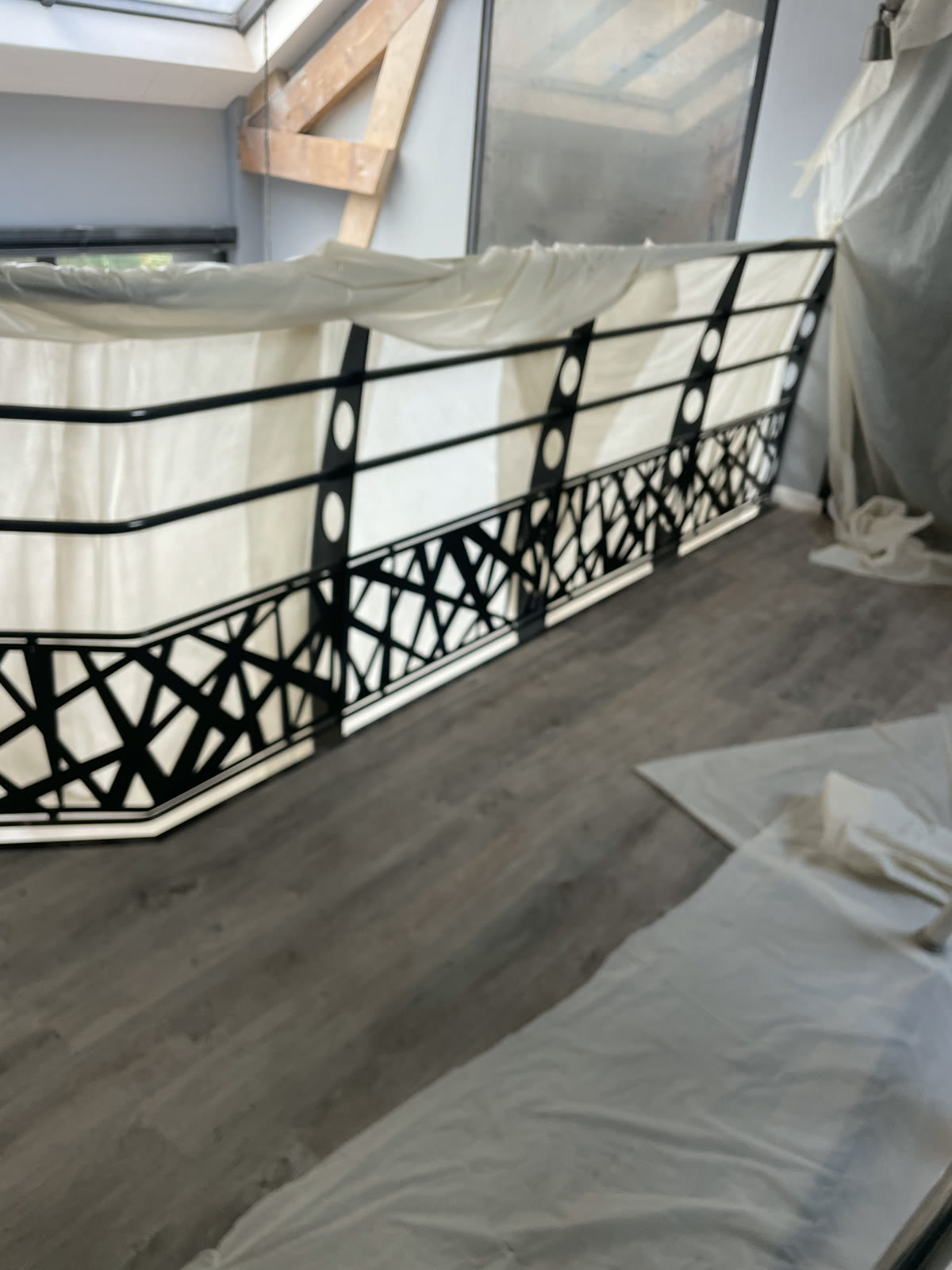 Mezzanine avec garde-corps noir, sol gris et protections de chantier autour des parois.