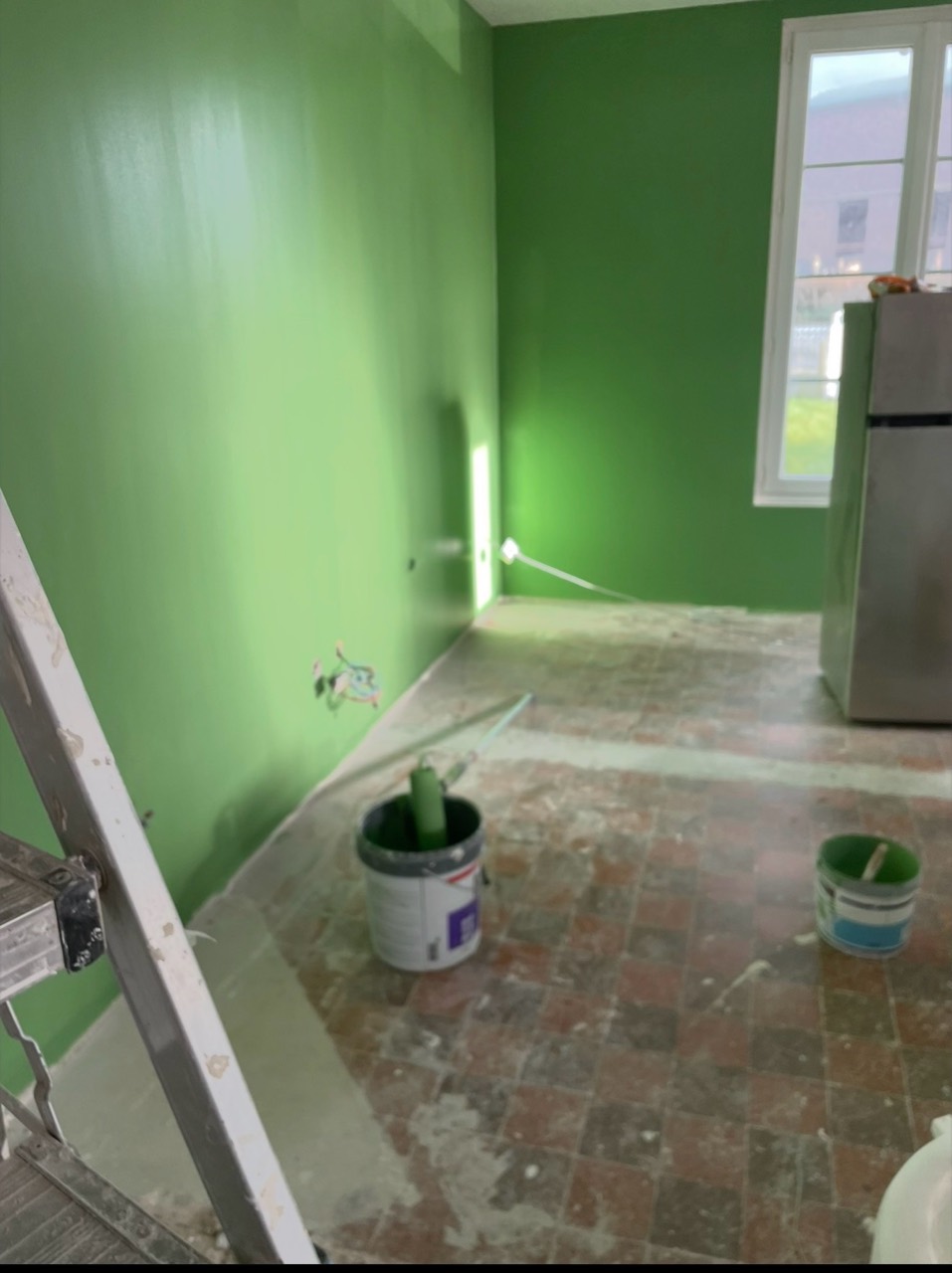 Mise en peinture verte d’une pièce avant la pose du revêtement de sol.