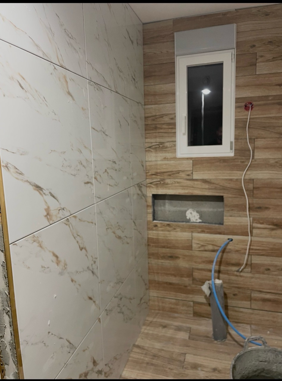 Carrelage mural effet marbre et bois dans une salle de bain en cours de création.