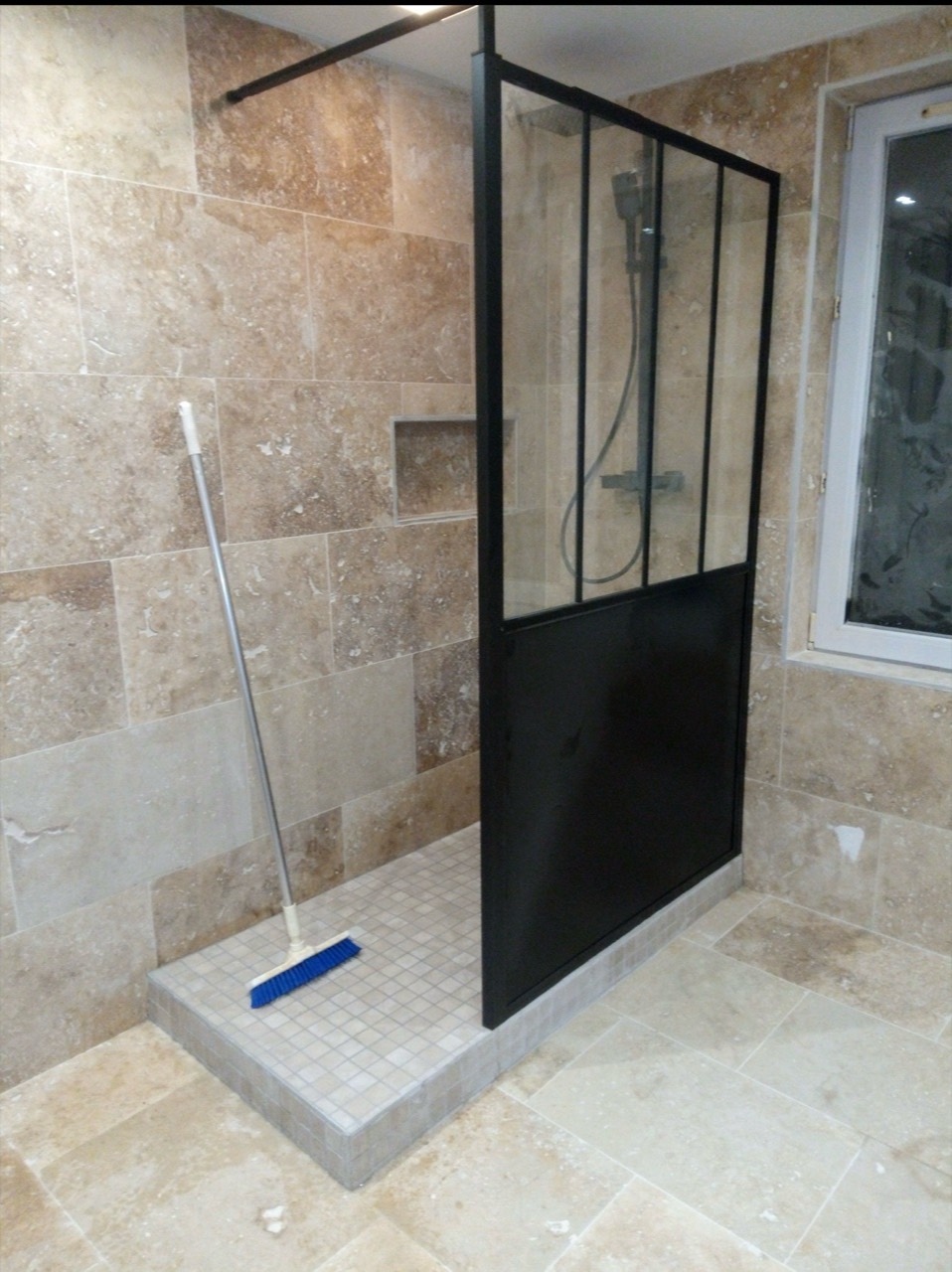 Douche carrelée aux tons pierre avec paroi noire de style atelier.
